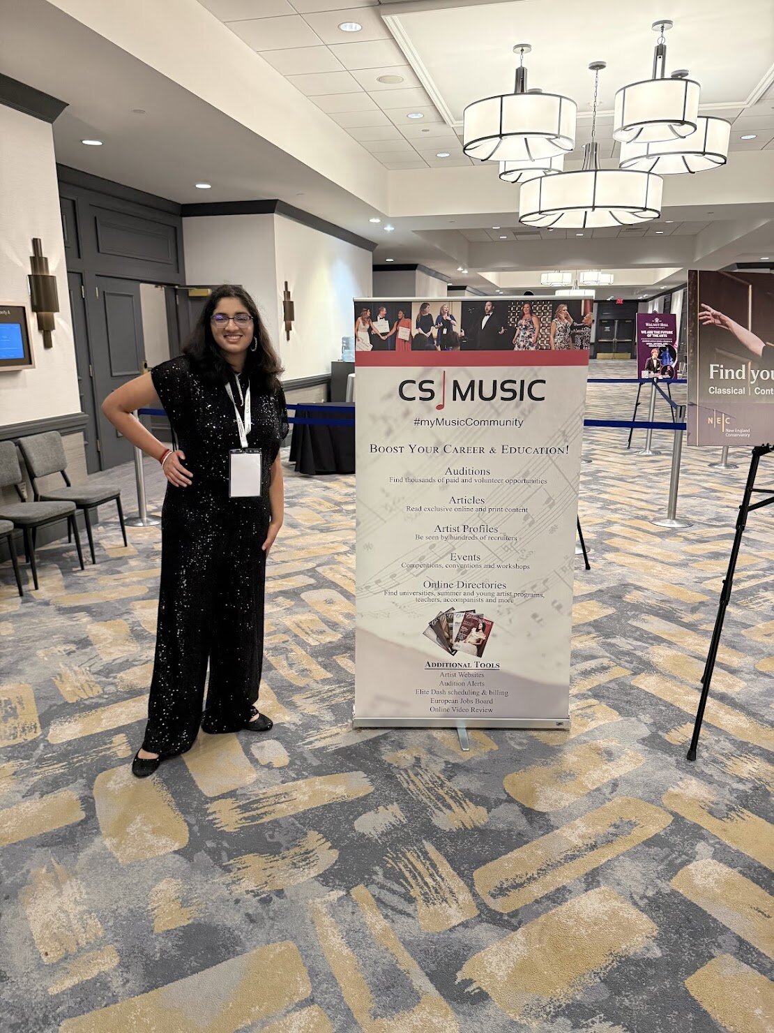 Ishaana at the CS MUSIC semifinal venue in Boston, standing next to the event banner